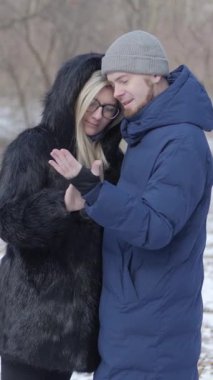 Sevgi dolu bir çift, karla kaplı sakin bir kış manzarasıyla çevrili iken sıcak bir kucaklaşmanın tadını çıkarır.