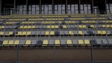 Bu boş stadyum tribünlerini gösteren bir manzara. Gri ve sarı koltuklar sırayla kullanılıyor.