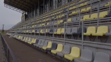 Boş stadyum tribünlerinin panoramik manzarasında çarpıcı bir gri ve sarı oturma düzeni görülüyor.