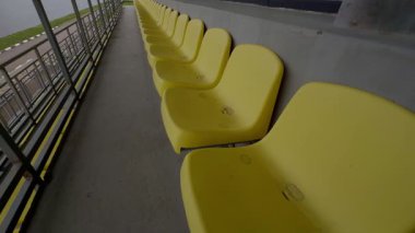 Modern çağdaş bir spor stadyumundaki boş sarı koltukların yakın çekim görüntüsü.
