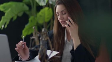 Kendini işine adamış bir iş kadını, ofisinde önemli belgeleri incelerken önemli bir telefon görüşmesi yapıyor.
