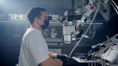 Odaklanmış bir cerrah, bir mikroskop kullanır, ileri tıbbi teknolojiyi klinik ortamda sergiler..