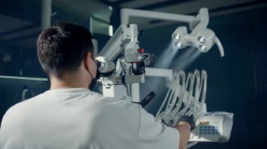 Yetenekli bir diş hekimi modern bir klinikte yüksek teknolojili mikroskop kullanır.
