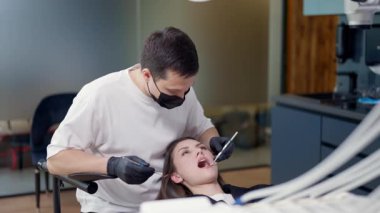Genç bir kadın şu anda modern, iyi donanımlı bir dişçi muayenehanesinde tam bir muayeneden geçiyor.