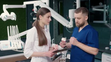 İki deneyimli diş hekimi modern bir diş sağlığı kliniğinde tedavi seçeneklerini tartışıyor