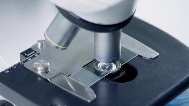 Yüksek güçlü bir mikroskop detaylı bilimsel analiz ve gözlemler için cam slaytı inceliyor.