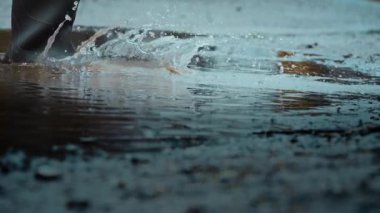 Kibar bir yağmurun hoş cazibesiyle neşeyle su birikintilerine sıçrarken şık lastik çizmeler giyerek