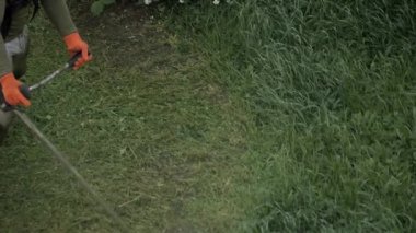 Çalışkan bir işçi, çim biçme makinesiyle çimleri dikkatlice budarken, bahçenin temiz ve bakımlı görünmesini sağlar.