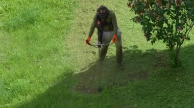 Çalışkan bir birey, güneşli bir açık havada verimli bir çimenliği ustalıkla budar ve yarda görünümünü güçlendirir.