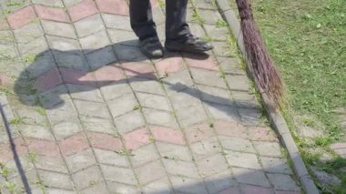 Kaldırımı temizlemek için süpürge kullanan ve herkesin keyif alması için temiz bir açık hava alanı sağlayan bir kişi.