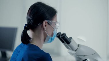 Bir laboratuvarda, bir birey bilimsel örnekleri mikroskop altında inceliyor.