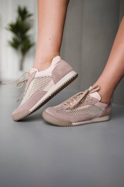 Şu anda yürüyen bir kadın şık ve modaya uygun bir çift pembe ve beyaz spor ayakkabı giyiyor.