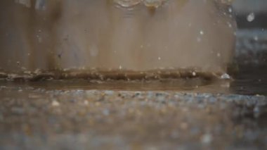 Yağmur suyunun su birikintilerinde lastik botlarla sıçrayan görüntüsü yağmurlu bir günün neşeli havasını güzel bir şekilde yakalıyor.