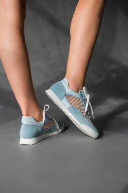 Bir kadın şu anda şık bir mavi ve bej spor ayakkabı giyiyor. Hem şık hem de rahat.