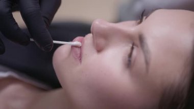 Yakın çekim, klinikte eğitimli bir profesyonelden canlandırıcı dudak tedavisi alan bir kadın gösteriyor.