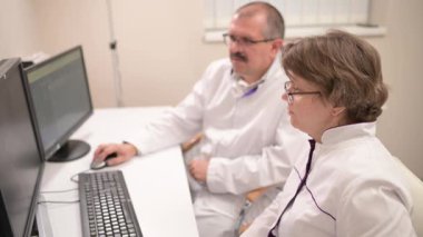 Gelişmiş bilgisayar sistemlerini işbirliğiyle kullanan iki sağlık uzmanı klinik ayar hasta verilerini gözden geçiriyorlar.