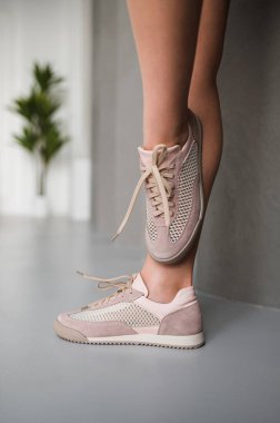 Şu anda yürüyen bir kadın şık ve modaya uygun bir çift pembe ve beyaz spor ayakkabı giyiyor.