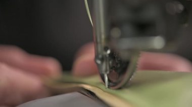 Bir dikiş makinesinin detaylı yakın plan görüntüsü kumaşı ustalıkla dikmek, hem hassasiyeti hem de zanaatı sergilemek.