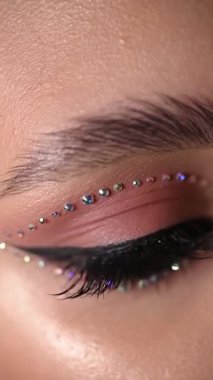 Göz kamaştırıcı yapay elmaslar ve büyüleyici bir görünüş için tasarlanmış kalın göz kalemi içeren göz kamaştırıcı bir makyaj.