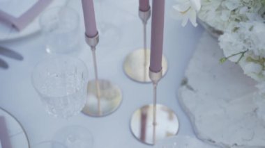 Beyaz düğün masasının üzerindeki mumları yakın plan çek. Yüksek kalite 4k görüntü