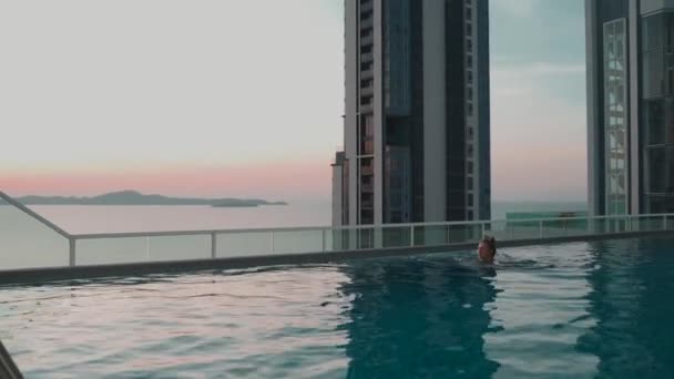Mujer Nadando Piscina Azotea Con Vistas Montaña Mar Rascacielos Atardecer — Vídeo de stock