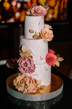 Gelin ve damat düğün ziyafetinde köy pastalarını kesiyorlar. Eller zarif pembe çiçeklerle pastayı keser..