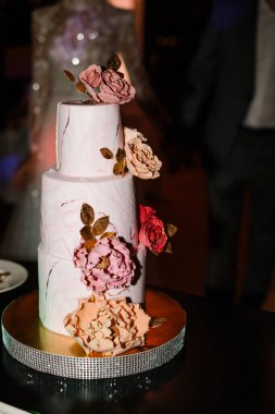 Gelin ve damat düğün ziyafetinde köy pastalarını kesiyorlar. Eller zarif pembe çiçeklerle pastayı keser..