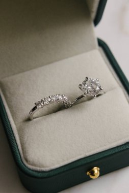 Göz kamaştırıcı bir elmas nişan yüzüğü ve alyans lüks bir kadife mücevher kutusunda güzelce sergilenmiş. Zarif ve zamansız gelin detaylarını göstermek için mükemmel..