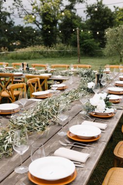 Tuscany kırsalında güzel dekore edilmiş yeşil çelenkler, beyaz tabaklar ve zarif camlarla süslenmiş bir köy düğünü..