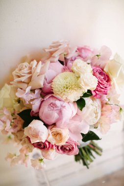 Güller, şakayıklar ve narin çiçeklerden oluşan pembe ve beyaz çiçeklerin karışımından oluşan romantik bir gelin buketinin çarpıcı yakın çekimi..