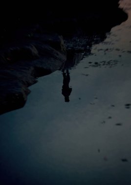 Bir kayanın üzerinde duran bir adamın nehrinde yansıması. 3 Boyutlu Hazırlama.