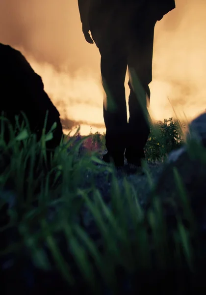 Mężczyzna Czarnym Garniturze Spaceruje Między Wysoką Trawą Skalistym Krajobrazie Podczas — Zdjęcie stockowe
