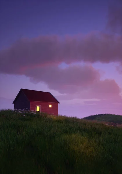 Cottage with lit windows in rolling pasture under a blue cloudy sky during sunrise. 3D render.