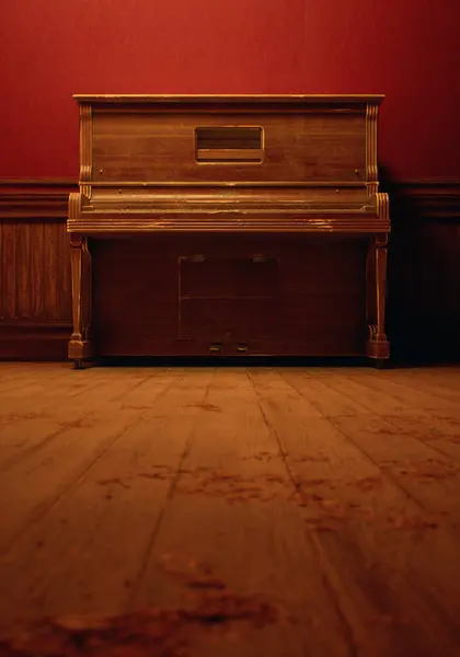木製のパネルが付いている赤い壁紙に対する木の床のヴィンテージのピアノが付いているヴィンテージの素朴な内部 ストックフォト