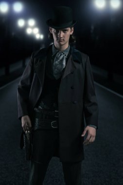 Gece sokakta elinde tabanca, şapkası ve paltosu olan genç bir Viktorya 'lı..