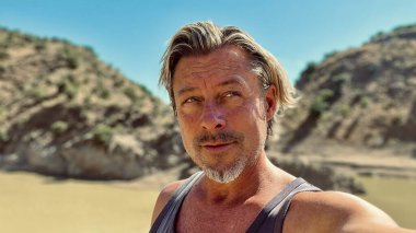 Bronz tenli, sarışın, sakallı, atlet gömlekli, güneşli bir ortamda..