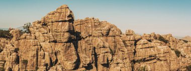 Mavi gökyüzünün altındaki yeşil bitki örtüsü arasındaki kireçtaşı kaya oluşumları. El Torcal de Antequera Ulusal Parkı. Endülüs. İspanya.