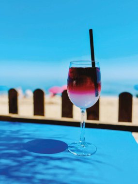 Mavi masanın üzerinde mavi bir gökyüzünün altında sahilde palmiye yaprağı gölgesi olan bir kokteyl. Endülüs, İspanya.