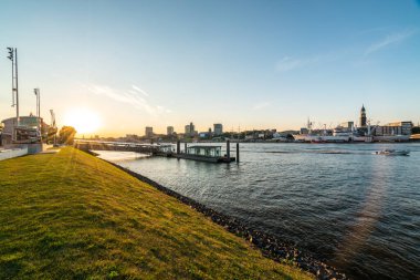 Hamburg rıhtımının büyüleyici günbatımı manzarası, canlı gökyüzü ve hareketli liman hayatı. Seyahat ve yaşam tarzı projeleri için mükemmel..