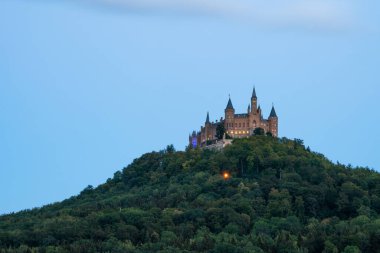 Stunning view of Castle Hohenzollern nestled among lush greenery during a serene summer evening. A perfect spot for travelers. clipart