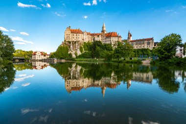 Bereketli yeşilliklerle çevrili sakin sulara yansıyan Schloss Sigmaringen 'in çarpıcı yaz manzarasını keşfedin..
