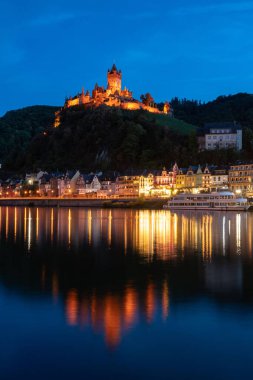 Capture the stunning reflection of Castle Cochem at dusk, showcasing idyllic summer vibes along the Moselle River. clipart