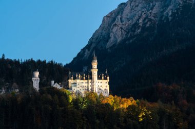 Neuschwanstein Kalesi 'nin çarpıcı manzarası alacakaranlıkta aydınlandı, Bavyera dağlarına yerleşti..