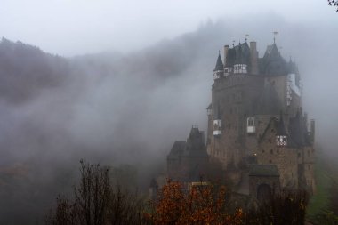 Discover the enchanting Eltz Castle shrouded in autumn mist, showcasing Gothic architecture amid colorful foliage. clipart