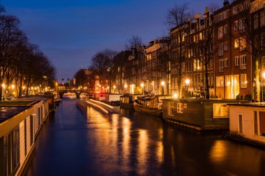 Alacakaranlıkta Amsterdam 'daki aydınlık kanalların göz kamaştırıcı manzarası romantik mimari ve sakin suları gözler önüne seriyor..