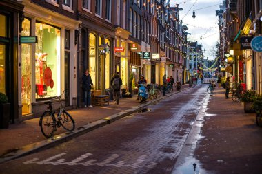 Amsterdam 'da bir akşamın büyüleyici atmosferini tecrübe edin, canlı dükkanlar ve kaldırım taşı caddelerinde kuyruk oluşturan bisikletlerle.