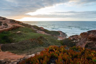 Portekiz, Peniche yakınlarındaki kayalık kıyı şeridi ve okyanus dalgaları serin günbatımında göz kamaştırıcı..