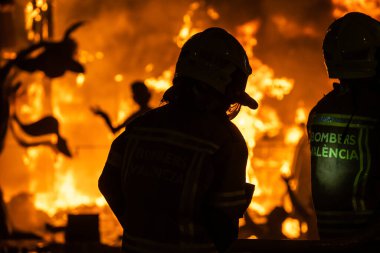 Valencias ikonik Fallas Festivali sırasında alevler geleneksel heykelleri yutarken cesur itfaiyeciler tetikte bekliyor..