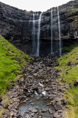 Yaz sonlarında Faroe Adaları 'ndaki yemyeşil yemlikler arasında çağlayan şelalelerin nefes kesici manzarası..