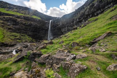 Yazın sonlarında Faroe Adaları 'nın yemyeşil tepeleriyle çevrili çarpıcı bir şelalenin güzelliğini hissedin..